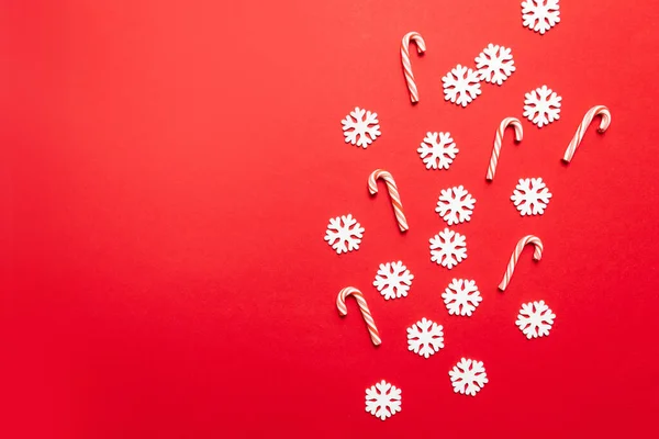 白い雪片とクリスマスの新年のデザインコンセプトは、パステルレッドの背景に多くのキャンディー杖を持つ — ストック写真