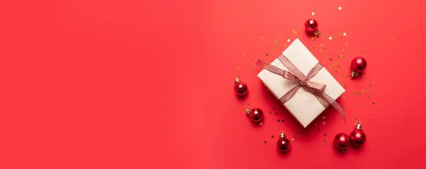 Kreativ sammansättning av presentförpackning med guld stjärnor dekoration, bollar på röd bakgrund. Minimalt nyårskoncept. — Stockfoto
