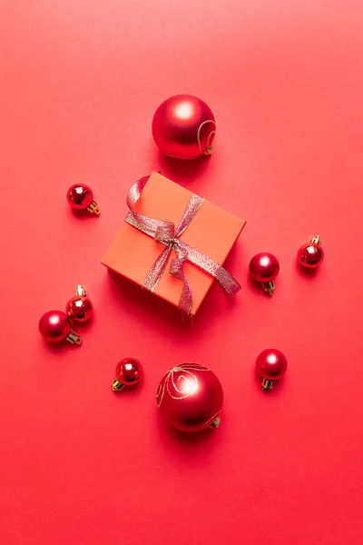 빨간 현재 상자, 리본, 빨간 크고 작은 공, 빨간 배경의 명절 장식 이 있는 크리스마스 포스터입니다. 평면 배치, 상단 뷰, 복사 공간 — 스톡 사진