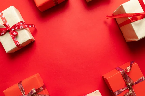 Karácsonyi kézműves ajándékdobozok piros háttér felülnézetből. Téli ünnep téma. Lapos fektetés. — Stock Fotó
