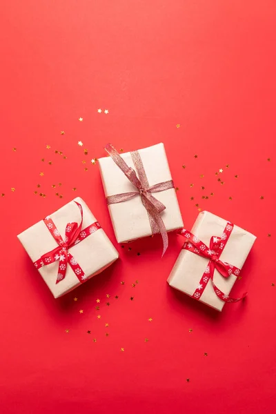 Composición creativa con caja de regalo roja, cintas decoraciones navideñas sobre fondo rojo — Foto de Stock