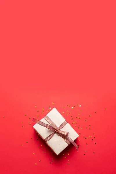 Composición creativa de la caja de regalo con arco de decoración de oro sobre fondo rojo. Diseño creativo plano, vista superior. Concepto de Año Nuevo mínimo . — Foto de Stock
