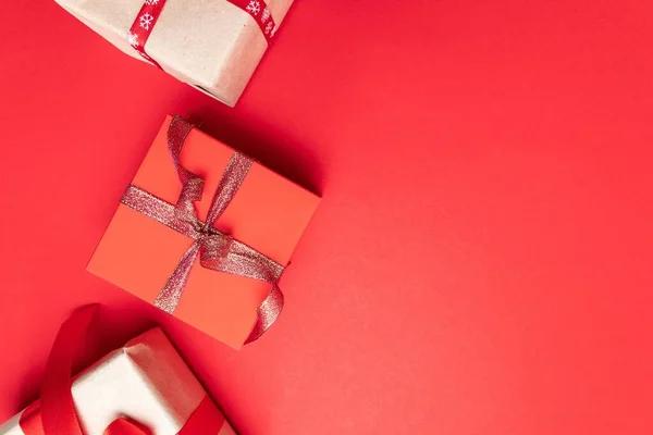 Moderna gåvor eller presenterar lådor med guldbågar och stjärna konfetti på röd bakgrund ovanifrån. Platt liggkomposition för födelsedag, jul eller bröllop. — Stockfoto