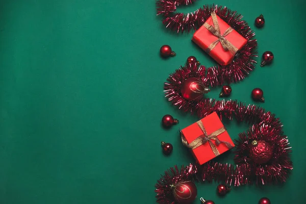 Kırmızı hediye kutusu, altın kurdele ve yeşil arka planda kırmızı toplar olan minimal noel konsepti. Düz konum biçimi kompozisyonu, üst görünüm. — Stok fotoğraf