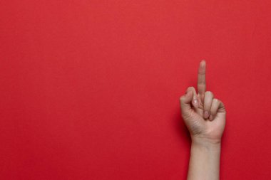 Kırmızı arka planda orta parmağını gösteren bir kadın eli. Düz konum biçimi