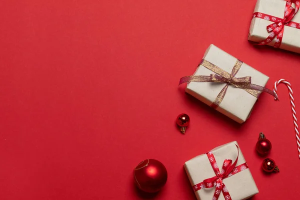 Adorno de Navidad decoraciones fondo con cajas de artesanía sorpresa, arco de cinta roja y bolas de bolas clásicas de vidrio rojo borde horizontal . — Foto de Stock