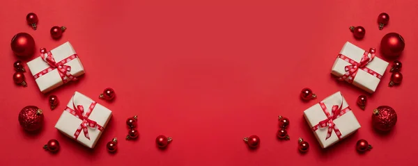 Winter xmas holiday greeting card with craft paper surprise boxes, big and small red balls on a red background with place for text. — ストック写真