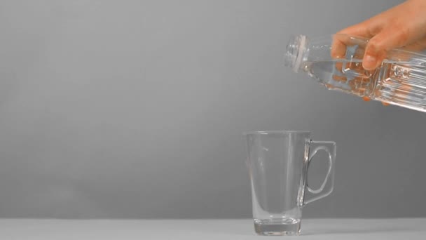 La mano femminile tiene una bottiglia d'acqua, versa acqua in un bicchiere — Video Stock