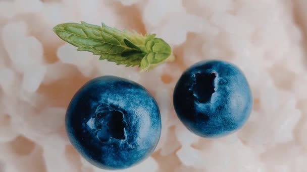 Chiusura di porridge di latte di riso con bacca di mirtilli su uno sfondo azzurro. Gustosa colazione sana — Video Stock