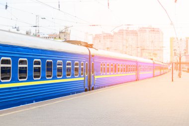 Gün batımında tren istasyonunda yerel tren. Tren peronunda tren.