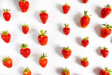 Gri arka planda, üst manzarada, düz bir zeminde leziz çilek deseni. Yaz kompozisyonu, asgari biçim