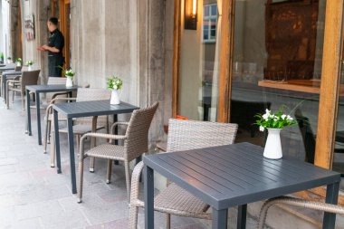 Dışarıdaki vazoda siyah masa ve beyaz çiçekli sandalye. Yazın açık hava kafeteryası.