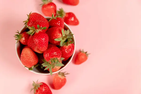 분홍색 배경에 있는 접시에 갓 익은 딸기, 맨 위에 보이는 것 — 스톡 사진