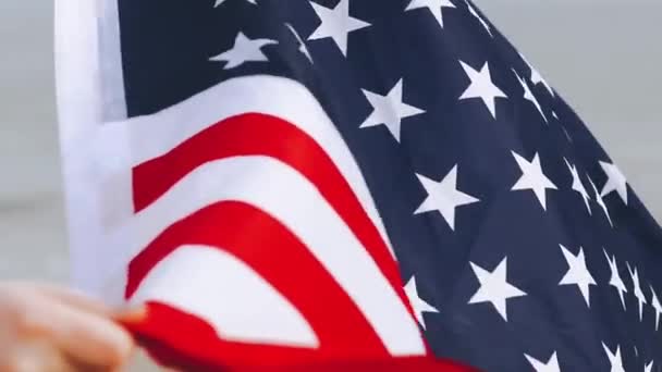 Gros plan des mains féminines tiennent drapeau des États-Unis sur la plage près des vagues de la mer. — Video
