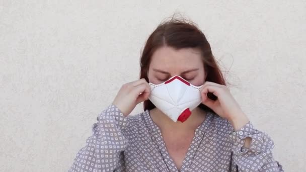 Eine junge Frau setzt sich eine medizinische Maske auf, um sich vor Viren, Keimen, Staub oder verschmutzter Luft zu schützen. Coronavirus und Covid-19 — Stockvideo