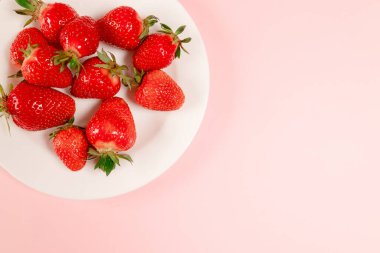 Üst görünüm beyaz plakalı çilek pembe zemin üzerinde, metin için yatay boşluk