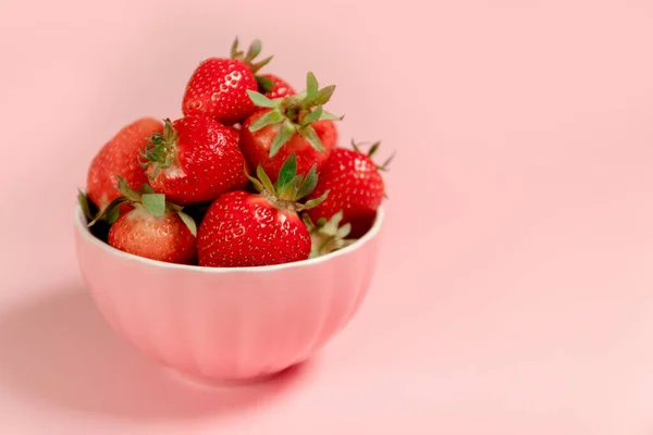 Schüssel mit frischen Erdbeeren auf rosa Hintergrund. — Stockfoto