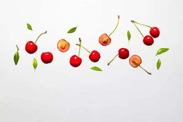 Cerezas maduras frescas orgánicas que caen con hojas verdes aisladas sobre fondo blanco . —  Fotos de Stock