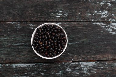 Düz bileşim, organik siyah frenk üzümü ile ahşap arka planda beyaz kasede yatıyordu.