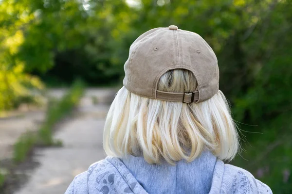 Sokakta beyzbol şapkası takmış sarışın bir kadının arkasından görüntü. — Stok fotoğraf