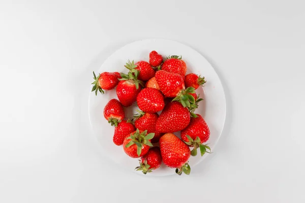 분홍색 배경에 흰색 접시에 있는 딸기 위를 바라봄. — 스톡 사진
