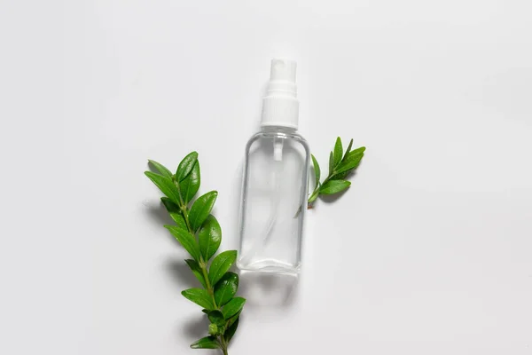 Натуральная пластиковая бутылка с жидкими и зелеными листьями на сером фоне . — стоковое фото