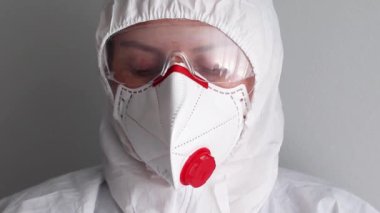 Coronavirus salgını sırasında koruyucu üniforma, gözlük ve maske takan bir kadının yüzünü kapatın..