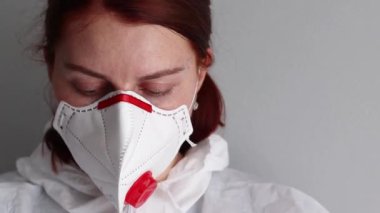 Kadın doktor, virüse karşı korunmak için maske ve koruyucu giysi takıyor. Salgın koronavirüs kovid 19.