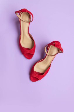 Mor zemin üzerinde kırmızı ayakkabıların düz kompozisyonu
