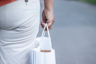 Kadın eli, bir müşteriye vermek için çevre dostu kağıt bir alışveriş çantası tutuyor. Güvenli bir teslimat. Ev paketleri için güvenli e-ticaret alışverişi.