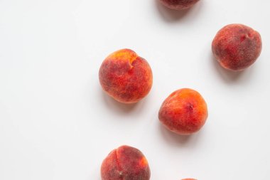 Taze şeftalilerin üst görüntüsü kaotik bir şekilde beyaz masada yatıyor.