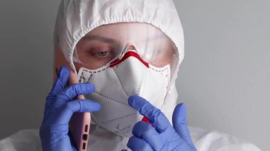 Maskeli doktor akıllı telefondan konuşuyor.