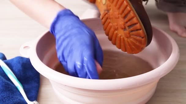 青いラテックス手袋の女性の手は、家の盆地で汚れた靴を洗う — ストック動画