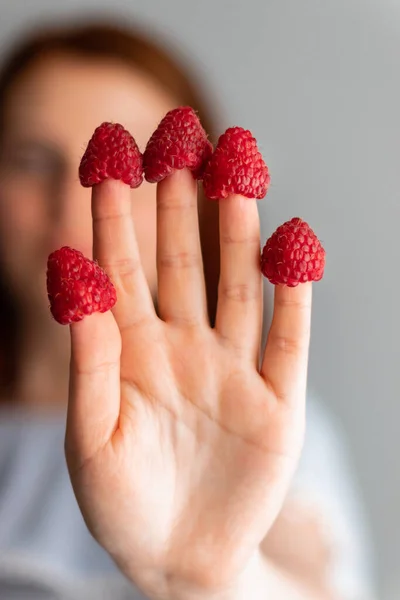 Young girl with raspberry berries on the fingers — Stock Photo, Image