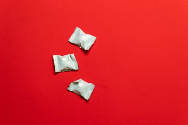 Pastel kırmızı arka planda şekerler. Düz yatış, üst görünüm