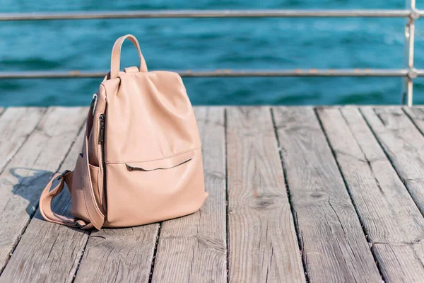 Ladies pink backpack on wooden deck of pier with ocean view in the summer