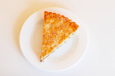 Sebzeli kapalı kiş turtası, ıspanaklı ve tavuklu beyaz tabakta, üst tarafta.