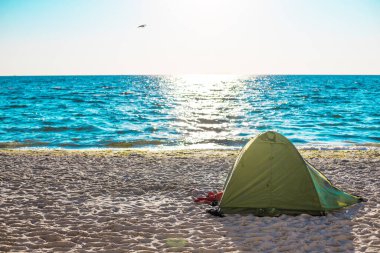 Gün doğumunda deniz kenarında turist çadırı. Seyahat, seyahat ve tatil konsepti