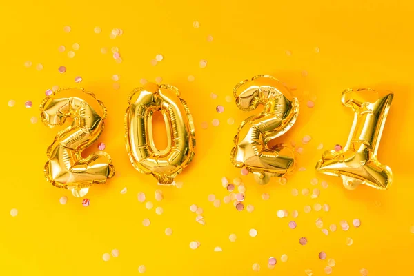 Mutlu yıllar 2021 kutlamaları. Sarı arka planda parlak yıldızlı parlak altın balonlar. Noel ve yeni yıl kutlaması.
