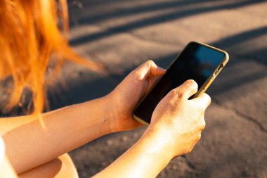 Öğrenci el ele tutuşup sokakta otururken akıllı telefon kullanıyor.