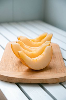 Ahşap masadaki beyaz kavun dilimlerinin renkli olgun meyve deseni. Yaz meyvesi konsepti. Dikey fotoğraf