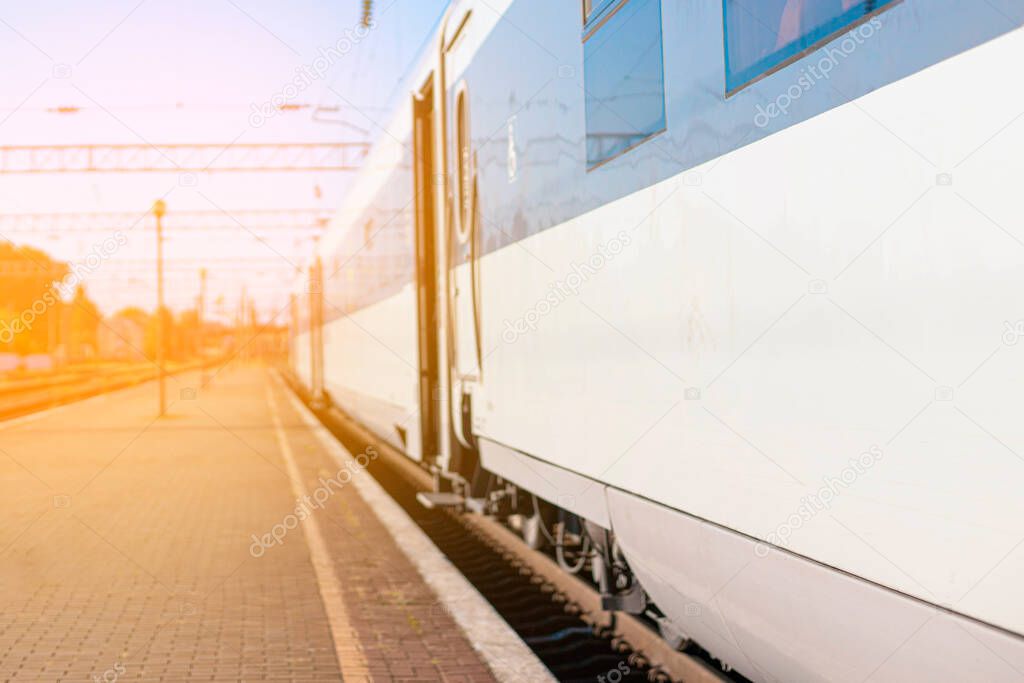 High-speed train on rails on the railway station platform on sunny day. Modern intercity train on railway platform. Travel concept