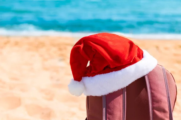 Santa kapelusz na turystę czerwony plecak na niebieskim tle — Zdjęcie stockowe