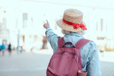 Sırt çantalı gezgin kadın ayakta duruyor ve eli sokakta yön gösteriyor. Seyahat yaşam tarzı.