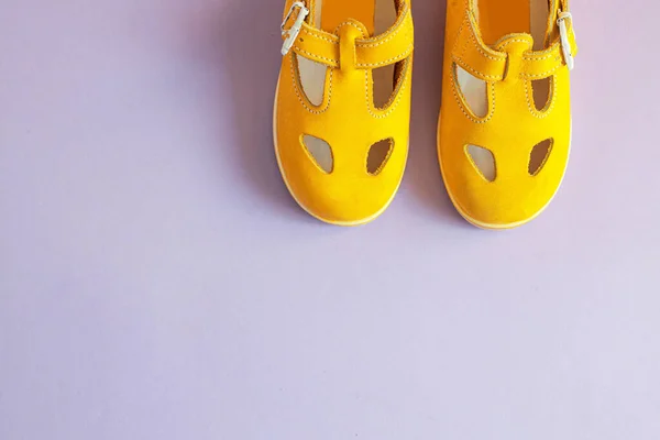 Sapatos de bebê amarelo brilhante em fundo lilás com copyspace. Conceito de roupa de bebé. Vista superior, flat lay — Fotografia de Stock