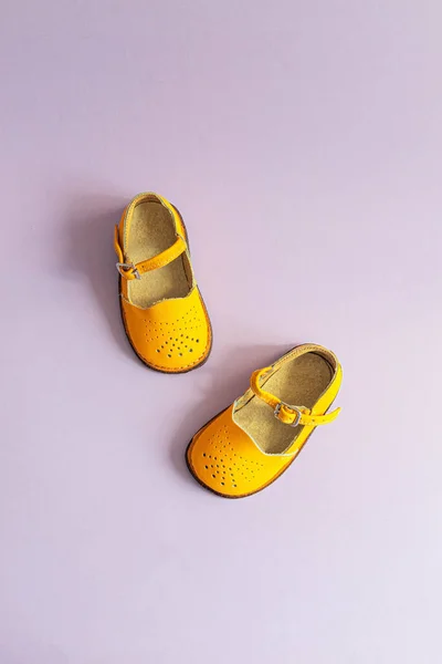 Sapatos de bebê amarelo brilhante em fundo lilás com copyspace. Conceito de roupa de bebé. Vista superior, flat lay — Fotografia de Stock