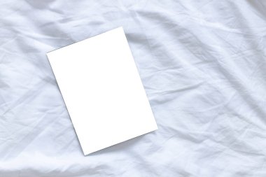 Beyaz çarşaf arka planında fotokopi alanı olan boş afiş kapağı. Üst manzara, düz uzanma