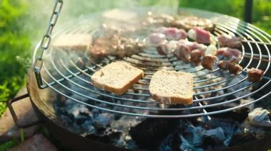 Barbekü ızgarasının kapanışı sıcak kömür üzerinde pişen ekmek ve et şişleri yaz güneşinde yükselen duman. Açık hava pikniği, geleneksel barbekü ve bayram kutlaması kavramı