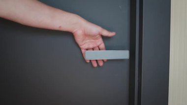 Modern metal kapıyı açarken erkeğin el ele tutuşunun yakın çekimi. Ev güvenliği, inşaat ve konut ayrıntıları kavramı. Güvenlik, gizlilik, kurulum ve modern yaşam tarzı sembolü.