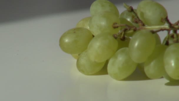 Escova uvas verdes postas em uma mesa branca — Vídeo de Stock